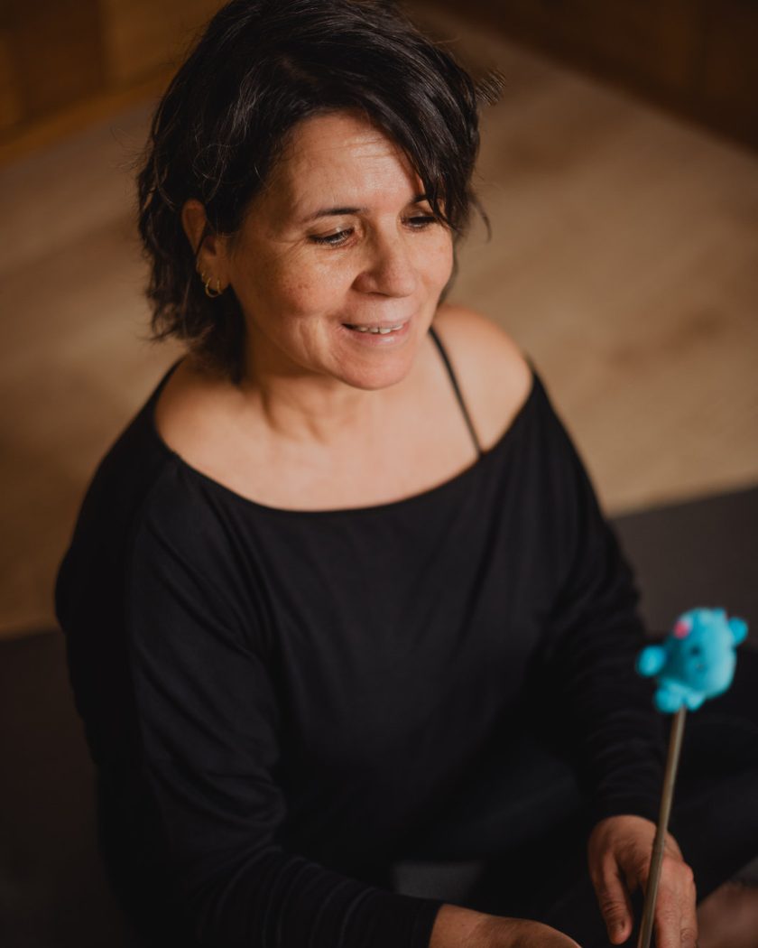 Raquel Devillé, thérapeute somatique à Virton, assise et souriante, tenant un pointeur de Brainspotting