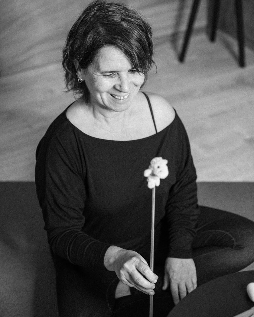 Raquel Devillé assise au sol, détendue, tenant un pointeur, photographie en noir et blanc