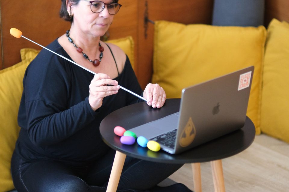 Séance de thérapie somatique à distance : Raquel Devillé assise au sol devant son ordinateur portable